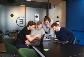 A diverse group of international researchers collaborating over laptops and documents in a bright modern lab.